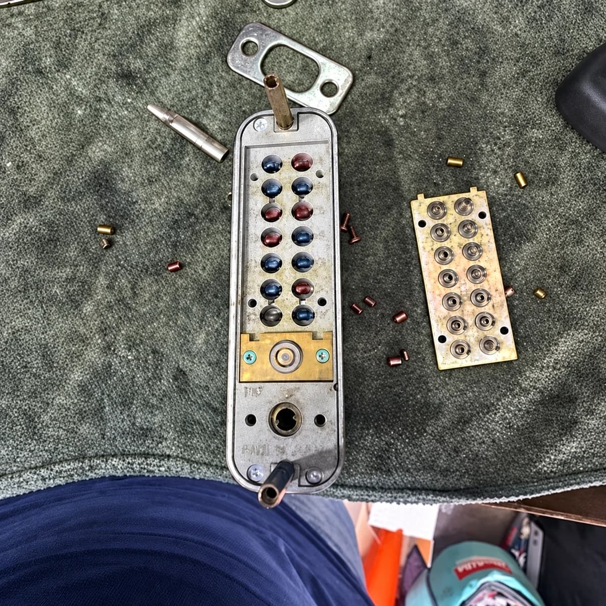 Dismantled mechanical pushbutton lock and loose components on a workbench