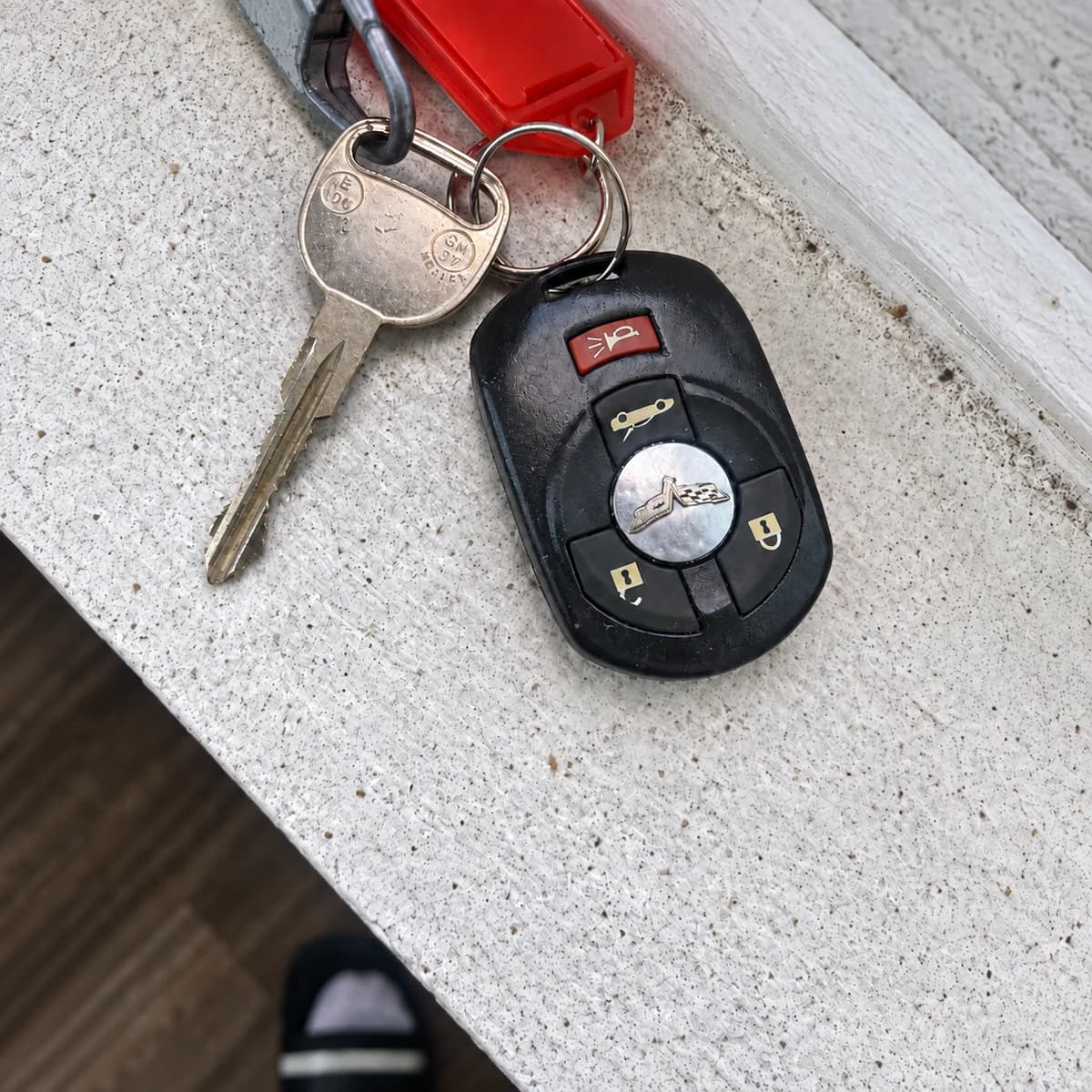 Metal car key and black remote on a light work surface