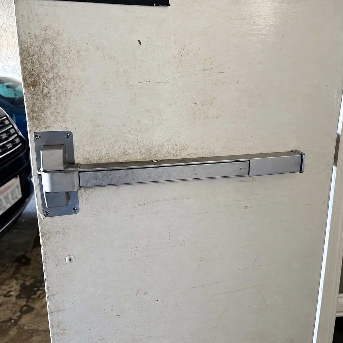 Metal exit bar fitted across a pale door