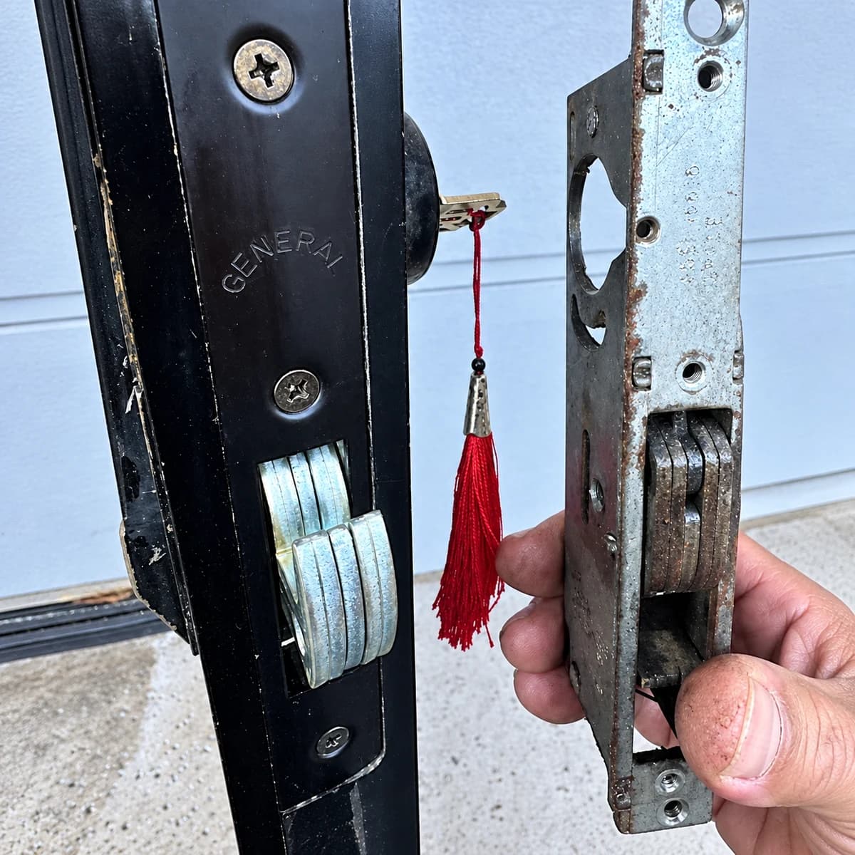 Installed dark lock hardware and separate held silver component with original red-tassel key in the center