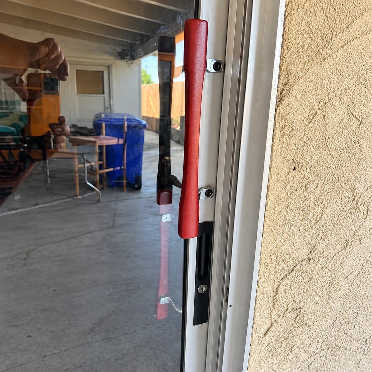 Red pull handle and lock hardware on an aluminum-and-glass doorway.